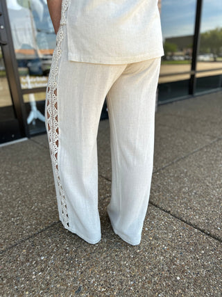 Allie Rose wide-leg linen pants with floral crochet lace side trim detail, worn outdoors.