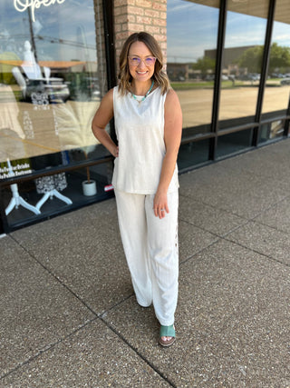 Woman wearing a sleeveless ivory linen top with V-neckline, styled with matching wide-leg pants.