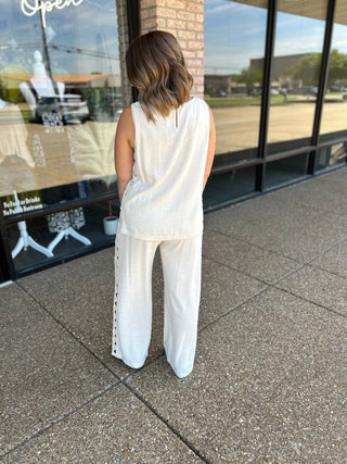 Woman wearing a sleeveless linen top with lace trim detail, paired with matching wide-leg pants.