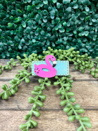Handmade kids hair clip with cute flamingo design on wooden surface with green plants