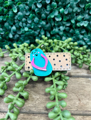Handmade kids hair clip with cute character design on wooden surface with green plants