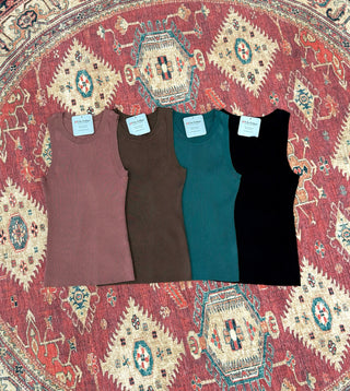 Four ribbed knit tank tops in different colors displayed on an ornate patterned rug