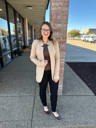Woman wearing brown ribbed knit tank top with beige blazer and black pants in professional outfit.
