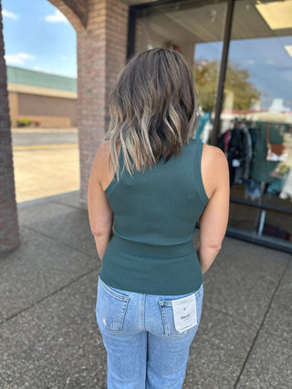 Woman wearing ribbed knit tank top and jeans, viewed from behind in outdoor setting.
