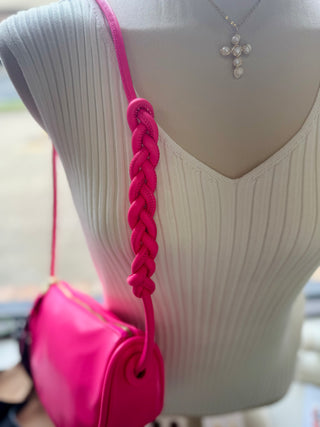 Woman wearing white ribbed top with pink crossbody bag featuring decorative braided shoulder strap