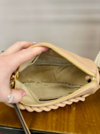 Hand holding open cream crossbody bag showing interior compartments and organizational pockets