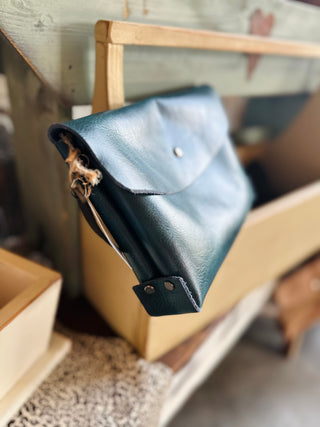Large leather envelope crossbody bag with flap closure and chain strap on wooden surface