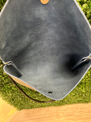 Large leather envelope crossbody bag with flap closure and adjustable strap displayed on textured surface