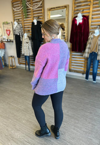 Woman wearing colorblock sweater in boutique store showing back view of fuzzy knit design