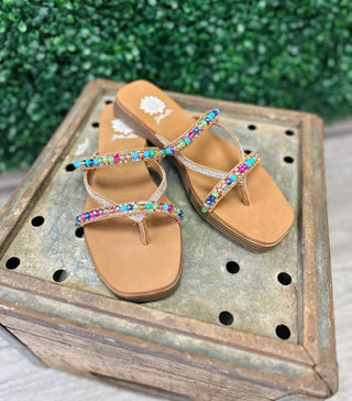 Lela bright beaded sandals with colorful gemstone embellishments and toe-post straps on wooden display tray.