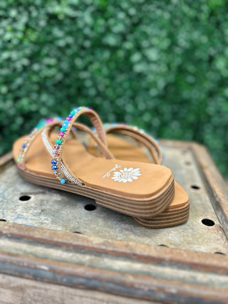 Beaded strap sandals with colorful jeweled embellishments and platform sole on wooden surface