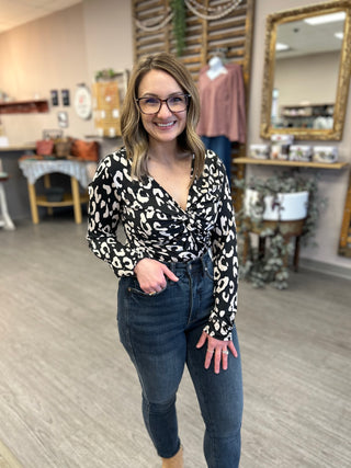 Woman wearing black and white leopard print twist front bodysuit with jeans in clothing boutique