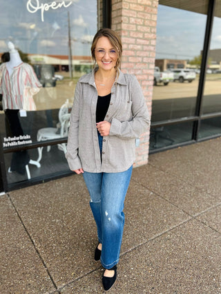 Woman wearing a striped button-front shacket layered over a black tank with jeans.