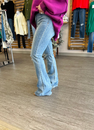Person wearing light wash high-rise distressed flare jeans with ripped knees in clothing store