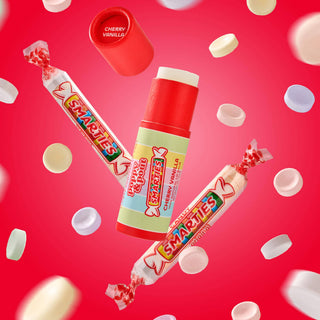 Poppy & Pout Smarties Cherry Vanilla lip balms floating with colorful candy pieces on bright red background