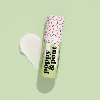 Poppy & Pout lip balm tube with colorful sprinkle pattern cap on green background