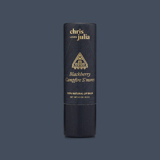 Black tube of Chris Loves Julia Blackberry Campfire S'mores natural lip balm with gold text and cabin icon.