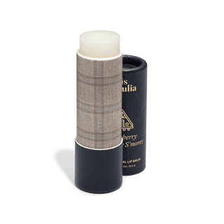 Poppy & Pout lip balm stick with textured tan tube next to dark cylindrical packaging