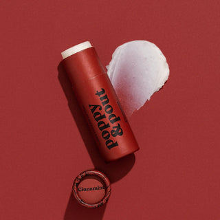 Poppy & Pout Cinnamint lip balm tube with white product application swatch on red background