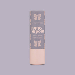 Poppy & Pout lip balm tube with gray packaging featuring pink bow pattern and peach base