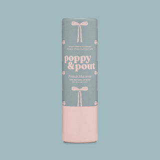 Poppy & Pout French Macaron lip balm tube with gray and pink packaging on light blue background.