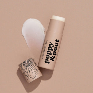 Poppy & Pout lip balm stick with floral design on neutral background, cap removed showing white balm