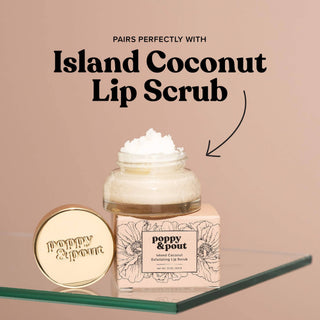 Poppy & Pout Island Coconut Lip Scrub jar with gold lid on glass surface against pink background.
