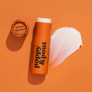Orange Poppy & Pout lip balm tube with cap removed showing white balm, product swatch visible