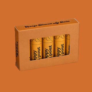 Orange packaging containing four tubes of Poppy & Pout Orange Blossom lip balm against orange background.