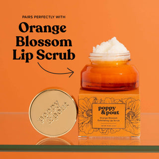 Orange blossom lip scrub jar with white scrub on top and round lip balm container on orange background.