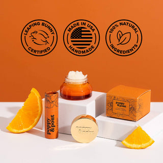 Orange-themed cosmetic products including lip balm, jar, and round container with certification badges and orange slices.