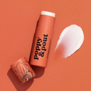 Poppy & Pout lip balm tube in coral packaging with white product smear on orange background
