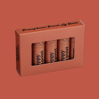Pomegranate Peach lip balm four-pack in coral packaging with window display against matching background