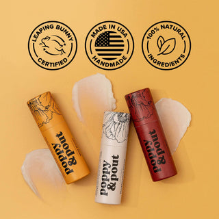Three Poppy & Pout lip balm tubes with certification badges showing Leaping Bunny, Made in USA, and 100% Natural ingredients.