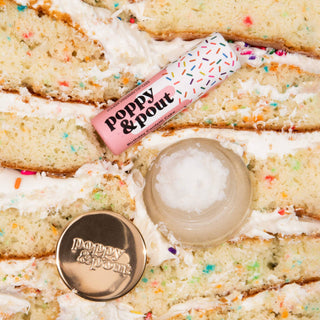 Poppy & Pout lip balm tube and lip scrub pot on colorful confetti cake background