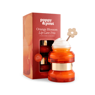 Poppy & Pout Lip Care Trio stacked amber jars with flower spatula beside branded gift box.