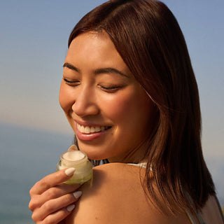 Woman smiling while holding Poppy & Pout Sweet Mint lip scrub jar in natural sunlight