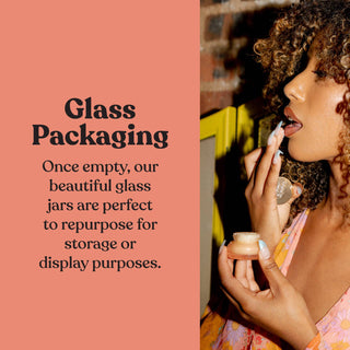Woman applying lip product from glass jar, demonstrating reusable glass packaging for lip scrub.