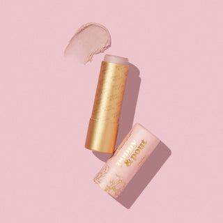 Poppy & Pout lip tint in golden tube with product smear and floral packaging on pink background