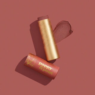 Poppy & Pout Debbie lip tint with golden tube and coral packaging on pink background with product swatch.