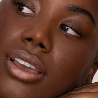 Close-up of woman's face showing natural makeup look with tinted lips and glowing skin.