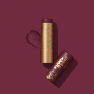 Poppy & Pout Lola lip tint with gold packaging and burgundy background showing product and box