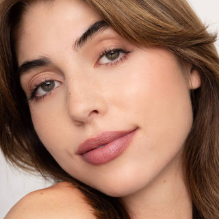 Close-up of woman wearing natural pink lip tint with glowing skin and brown hair