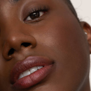 Close-up of a woman's face showcasing natural lip tint with a subtle glossy finish.