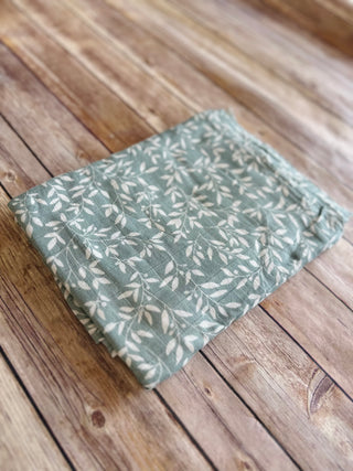 Folded baby blanket with leaf pattern on wooden deck flooring