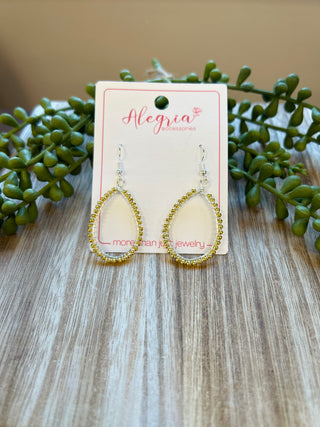 Teardrop-shaped earrings with beaded trim displayed on branded card with succulent plants on wood surface.