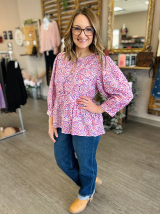 Woman wearing paisley patterned blouse with jeans in clothing boutique store setting