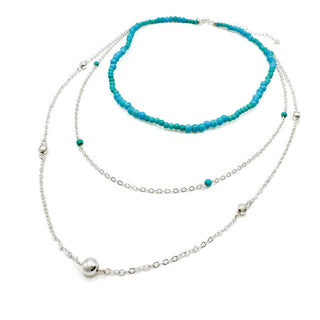 Multi-layered beaded necklace with turquoise stones and silver chain details on white background