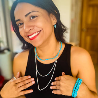 Woman wearing layered necklaces and turquoise jewelry, smiling while showcasing the Make Waves Necklace collection.