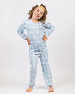 Young girl wearing light blue star-patterned holiday pajama set with long sleeves and pants.